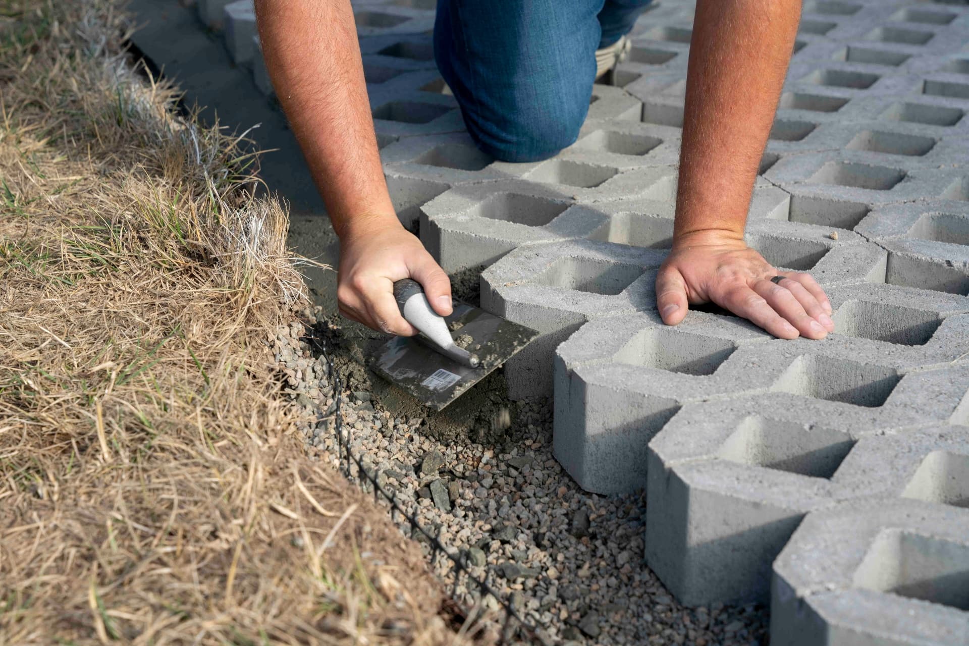 Hands installing concrete paving stones